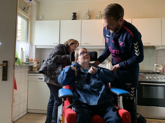 Willem Janssen van FC Utrecht verrast mantelzorger An Doornkamp in Driebergen en helpt dochter Debbie in haar jas om samen boodschappen te doen in het kader van Mantelzorgcampagne Zorg van de Zaak en FC Utrecht