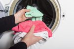 woman louding laundry into washing machine